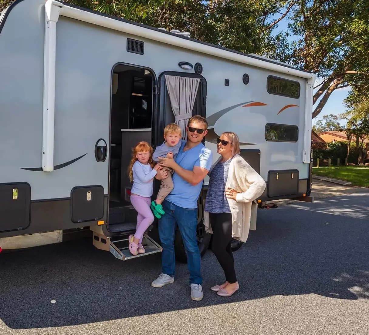 A family standing at the open door of their caravan