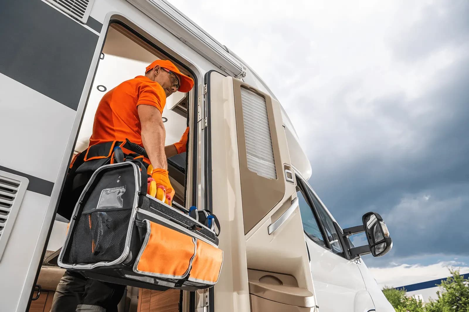 A Kennedy RV technician carrying a tool bag into the door of a motorhome